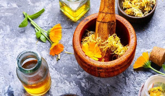 preparing calendula oil by crushing petals in a pestle and mortar andand steeping in oil